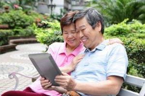 happy Senior couple using tablet pc in nature park, asian family