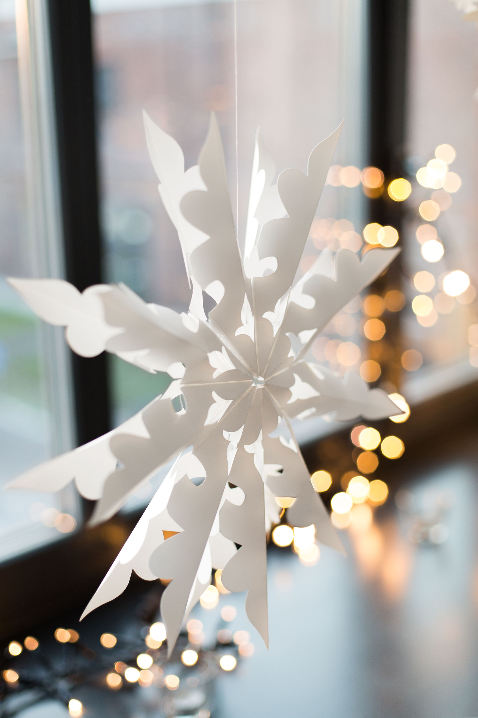 christmas and holidays concept - paper snowflake decoration hanging on window